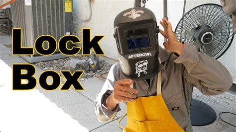 Welding a lockbox to an existing metal gate. 